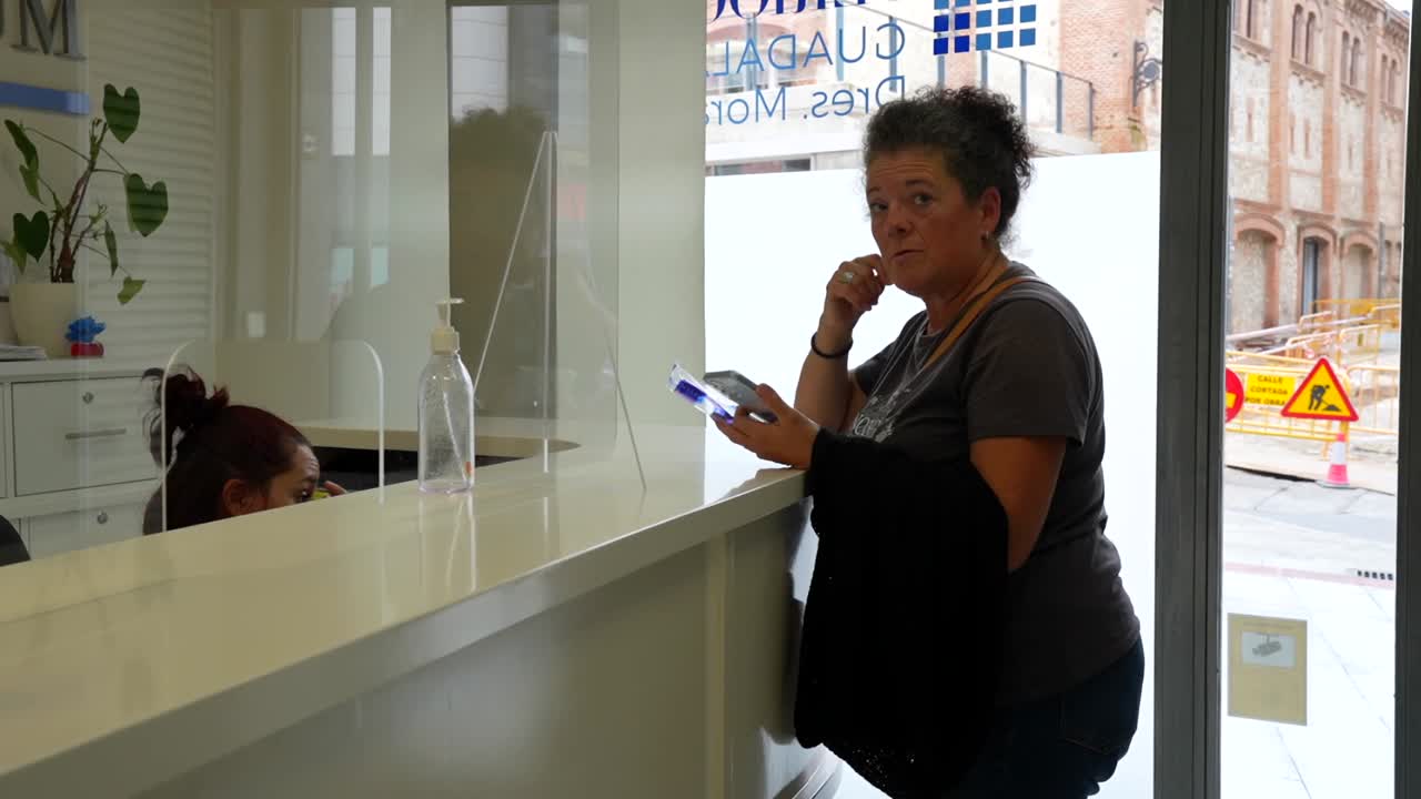 mujer esperando en la recepción de la clínica dental, usando el teléfono para comprobar las fechas disponibles para la próxima visita
