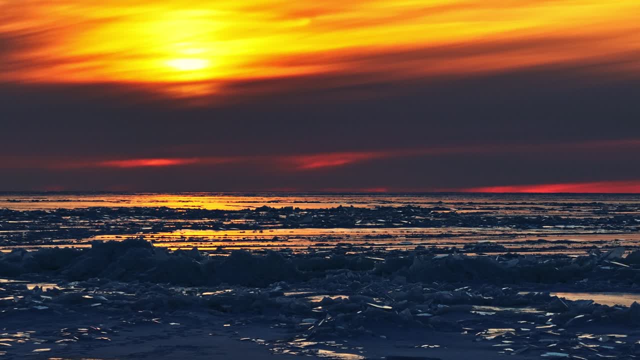Gefrorene Eisschollen der Ostsee, die dramatische orangefarbene Sonnenuntergangsfarben widerspiegeln, natürlicher Hintergrund mit Eisformationen und Platz für Text.