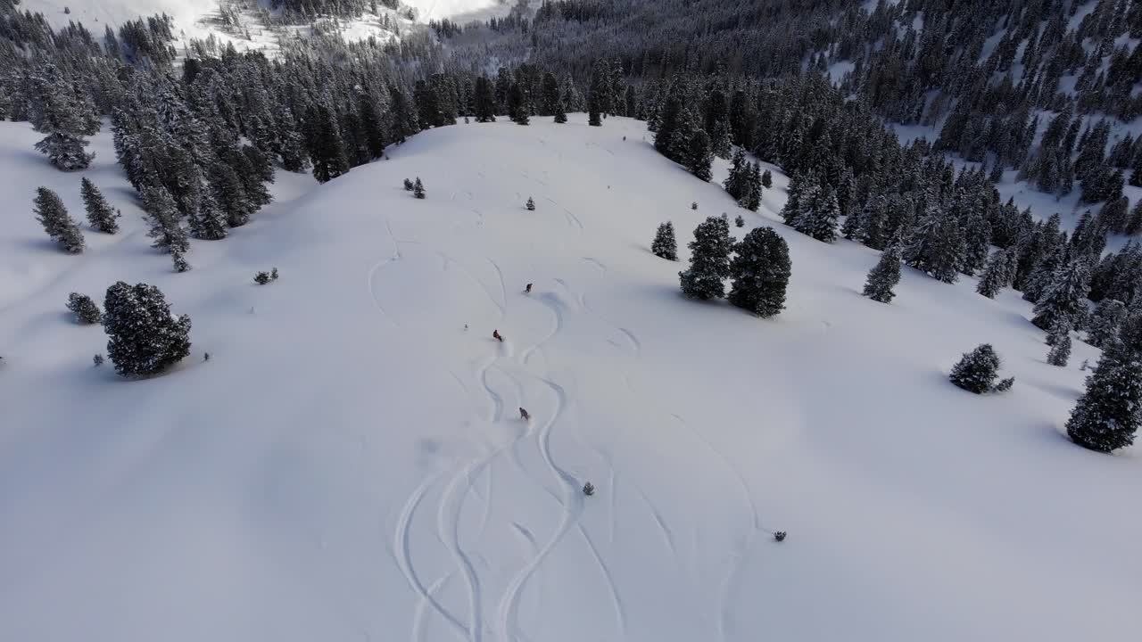 Drone che segue tre snowboarder in azione mentre eseguono belle curve su una grande montagna backcountry in Austria.