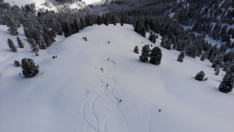 drone siguiendo a tres snowboarders en acción haciendo hermosos giros en una gran montaña de campo en austria