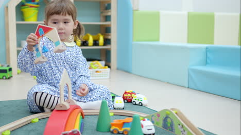 creative 3-year-old toddler girl playing toys sitting on rug building car road