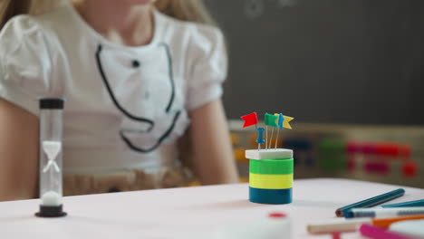 little girl builds tower with eraser and small flags on top