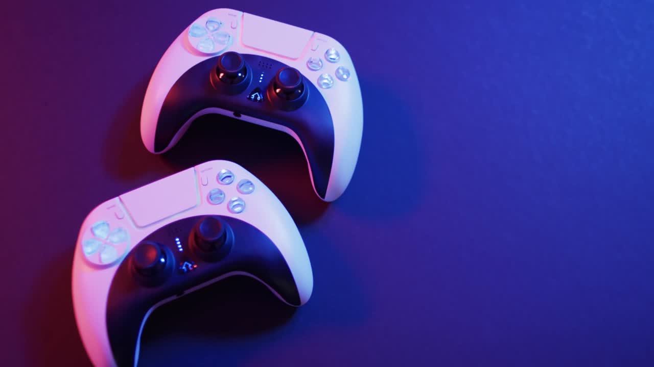 Video of close up of video game pad controllers with copy space on neon background