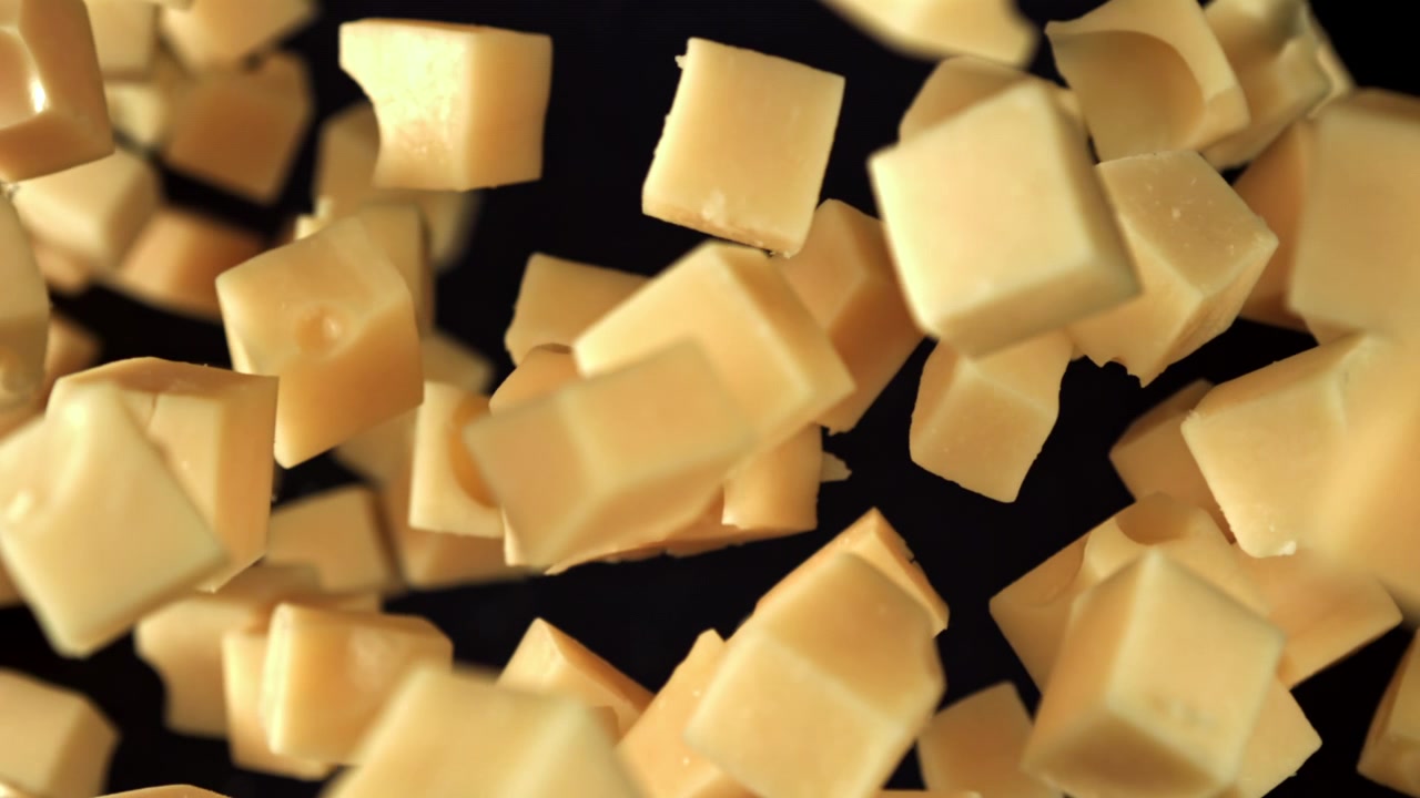 Cubes de fromage tombant au ralenti sur fond noir