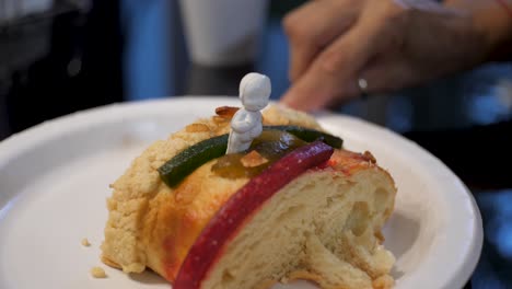 Ein-Stück-Rosca-De-Reyes-Mit-Einer-Figur-Des-Jesuskindes-Darauf,-Ein-Traditionelles-Mexikanisches-Süßes-Brot