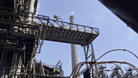 Big-industrial-building-with-old-metal-structure,-lots-of-old-pipes-and-cables-in-nice-weather