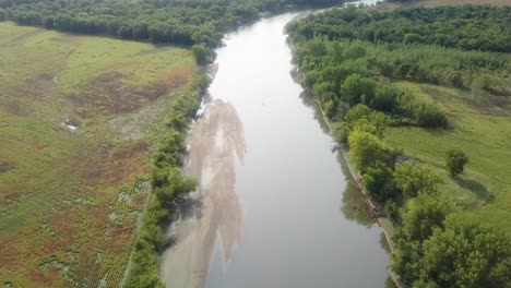 Vista-Aérea-De-Drones-Siguiendo-El-Sendero-De-Agua-Del-Río-Iowa-Con-Un-Gran-Banco-De-Arena-En-El-Río