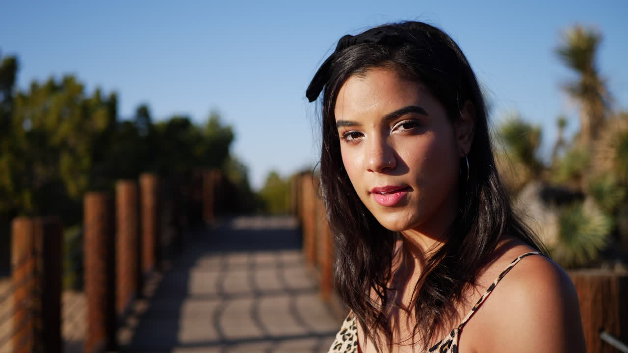 una hermosa mujer hispana modelando y posando con ojos serios al aire libre en un paisaje natural desértico al atardecer