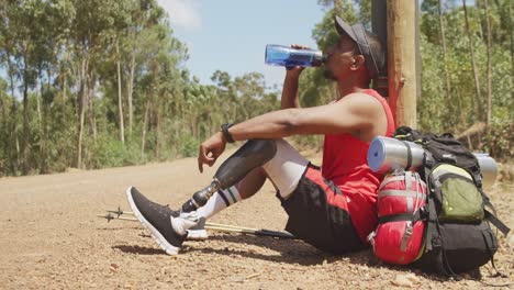 sporty mixed race man with prosthetic leg drinking water