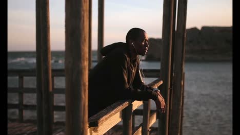 african american male jogger standing on pier at beach in the sunshine 4k