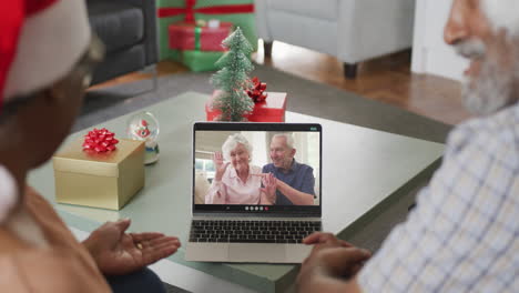 feliz pareja afroamericana en videollamada en computadora portátil con amigos mayores en tiempo de navidad