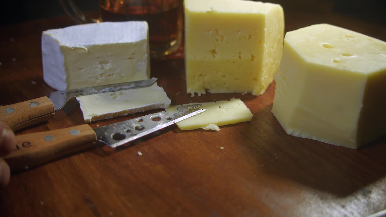 los quesos brie y gouda se cortan de cerca en una tabla de corte de madera