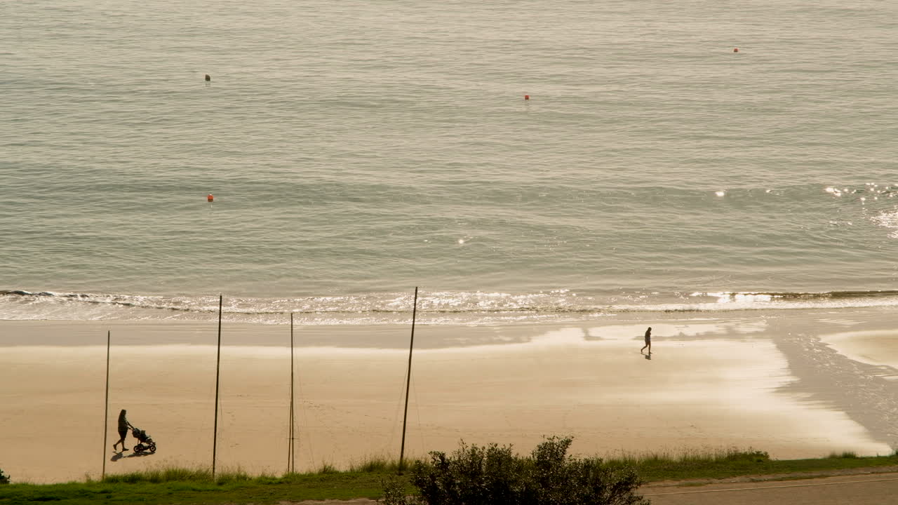 persona con un cochecito de tres ruedas en la playa de santos al amanecer
