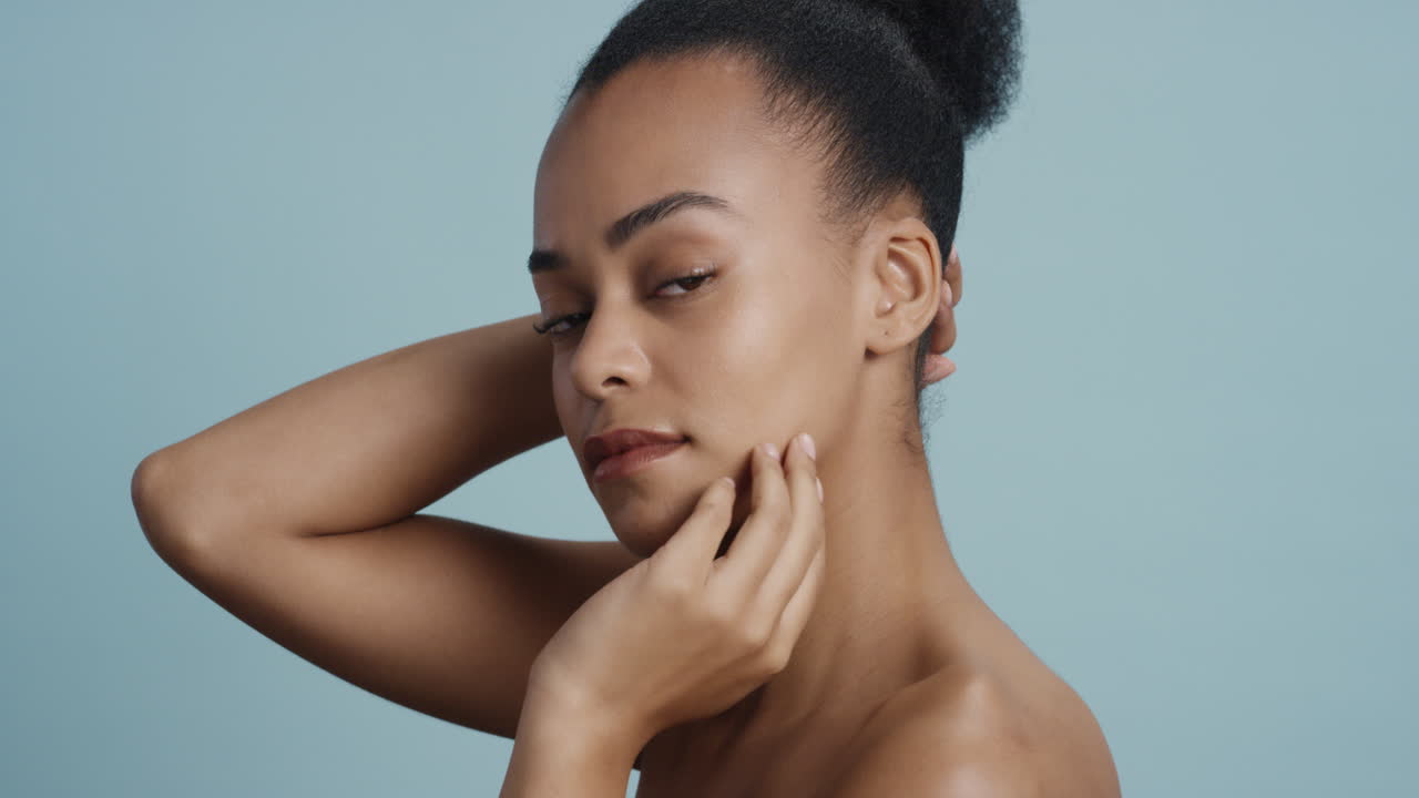 portrait beautiful african american woman touching body with hand caressing smooth healthy skin complexion enjoying perfect natural beauty looking confident on blue background skincare concept