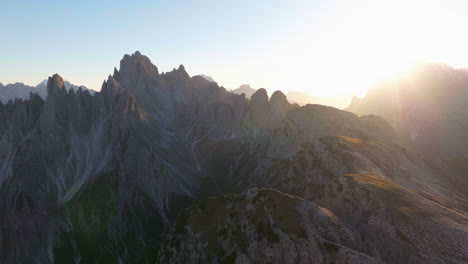Glowing-sunlit-Tre-Cime-mountain-peaks-and-summit-aerial-view-across-South-Tyrol-shining-sunrise-panorama