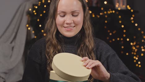 Young-Woman-Embracing-Festive-Joy,-Holding-a-Wrapped-Christmas-Gift