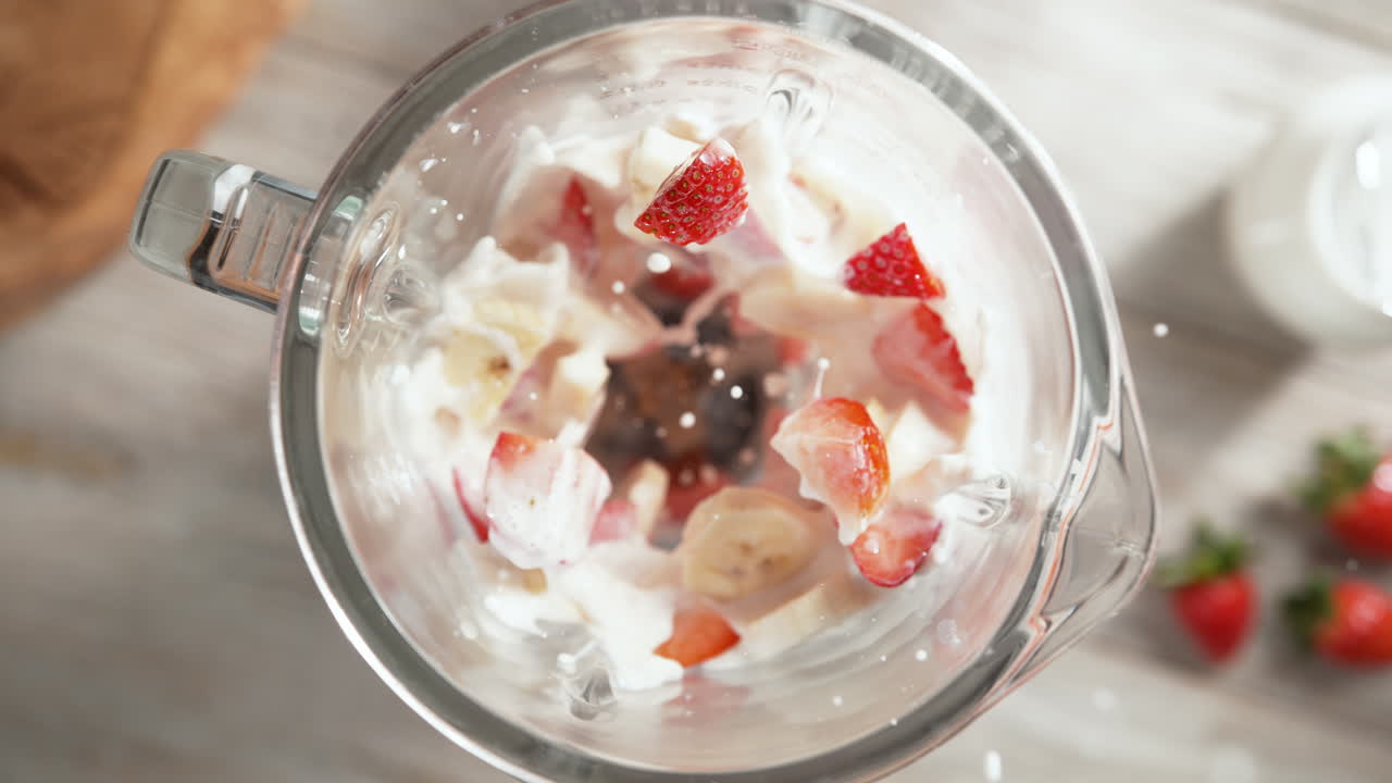 딸기와 바나나 밀크 이크가 유리 블렌더에서 느린 동작으로 여, 위쪽 시각, 장치 내부