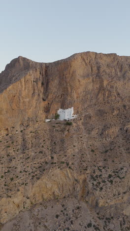 holy monastery of the virgin mary chozoviotissa, the panagia hozoviotissa monastery on steep cliff at sunrise, amorgos island, aerial vertical shot