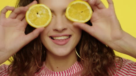 mujer feliz divirtiéndose con mitades de limón en el estudio. rostro de modelo de moda sonriendo