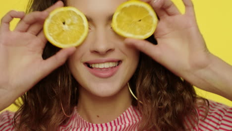 happy woman having fun with lemon halves in studio. fashion model face smiling