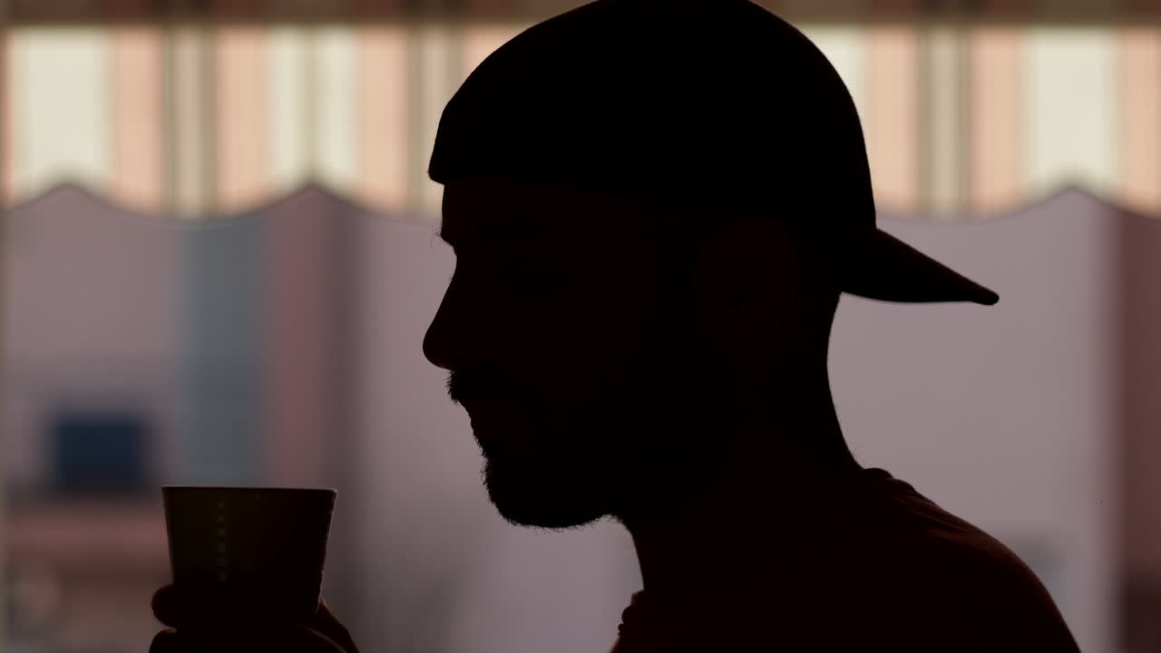 느린 동작:야외에서 차나 커피를 마시는 남자의 실루엣