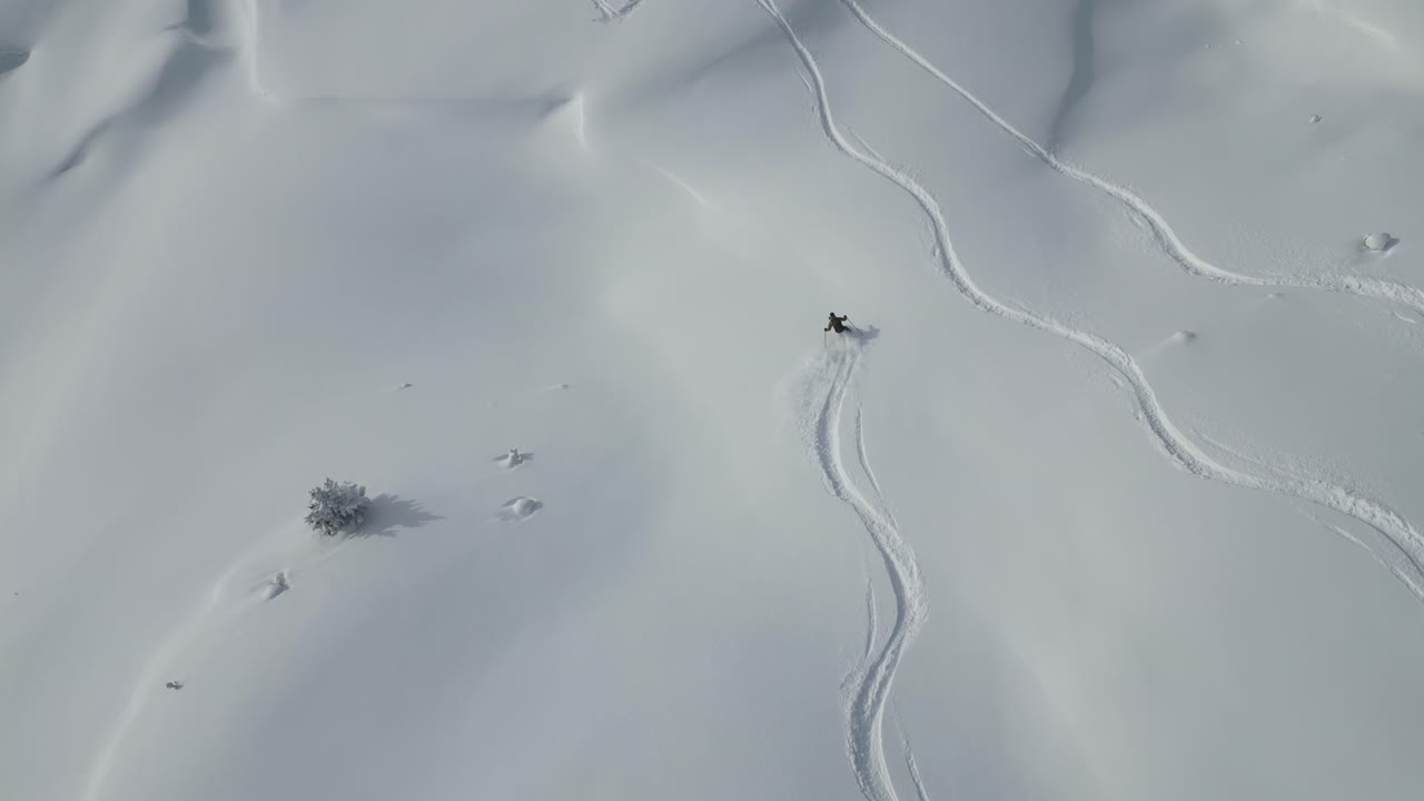 aéreo siguiendo a un joven esquiador deportivo por el glaciar cubierto de nieve paisaje de la cordillera en un paisaje alpino nevado