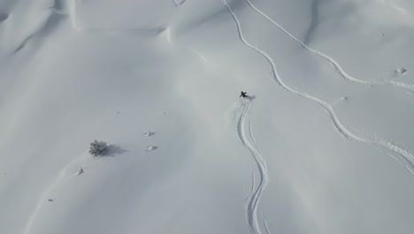 aerial following young sports skier down snow covered glacier mountain range scnery in snowy alpine scenery