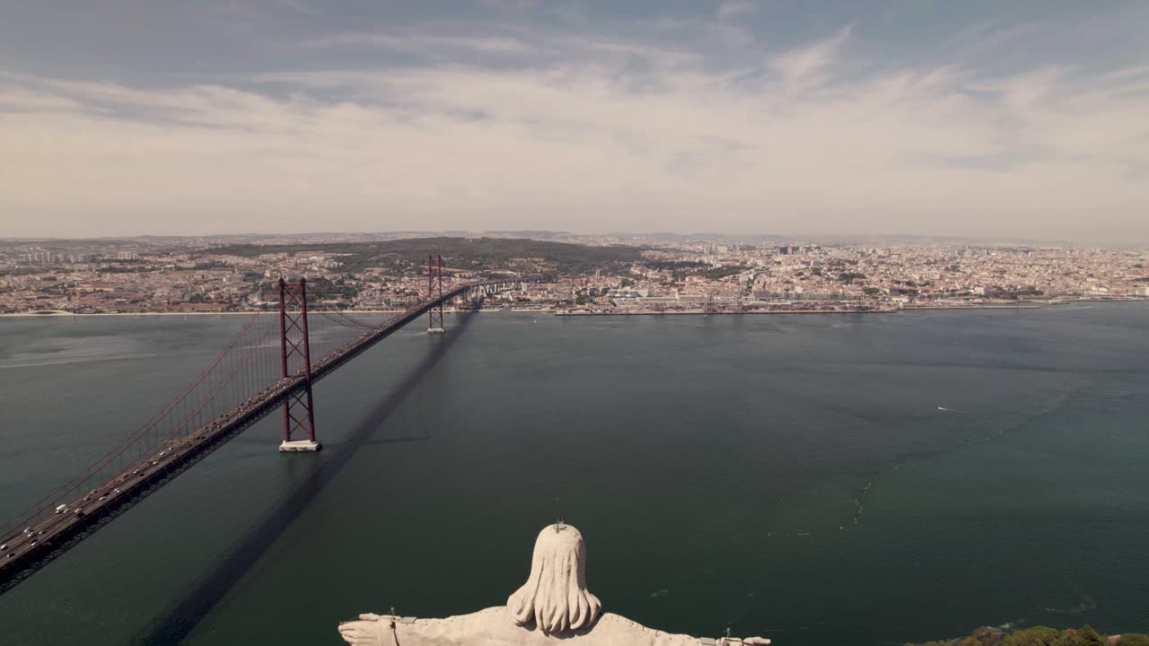 Tomada aérea com afastamento da parte de trás da estátua católica Cristo Rei em Almada, com vista para Lisboa