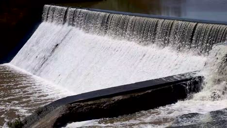 dynamic close-up of water rushing over a small dam's spillway, capturing the power and flow. perfect for nature, environment, and water management projects