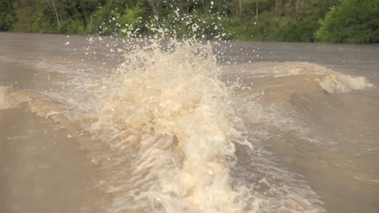 Slow motion waves behind a boat on a murky river in Colombia