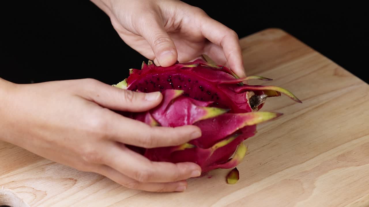 Hands slicing and displaying vibrant dragon fruit