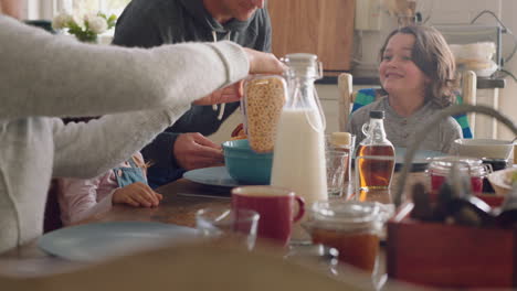 familia feliz desayunando juntos padres preparando cereales para los niños en la cocina en casa