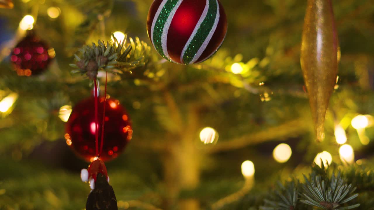 Rising View of Festive Christmas Fir Tree with Aesthetic Bokeh and Ornaments including Bourballs and Xmas Lights on Branches. Holidays Seasonal Footage 4K Video Background.