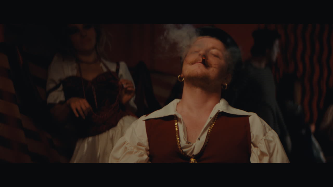 A man in hat sits down to the play in the gypsy circus camp