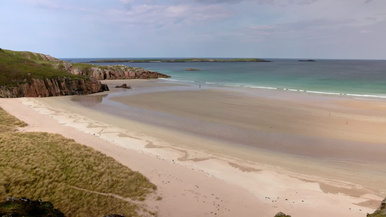 turquoise water at the beautiful Ceannabeinne Beach with tourists exploring