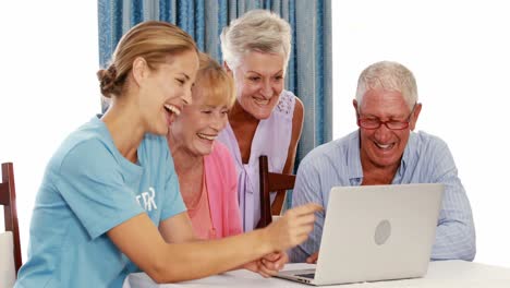Female-volunteer-and-senior-citizens-using-laptop
