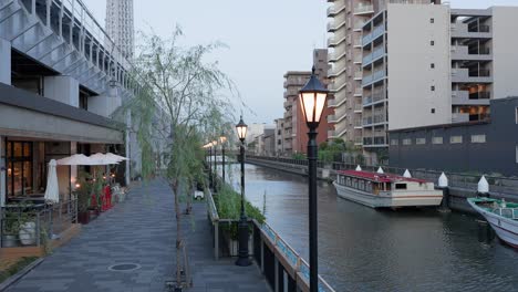 a shot capturing the stylish cityscape of tokyo mizumachi with its cafes and restaurants lining a well-maintained canal. a tour boat is also floating on the canal
