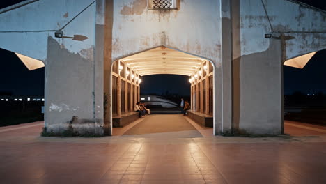 people waiting at an illuminated train station entrance at night