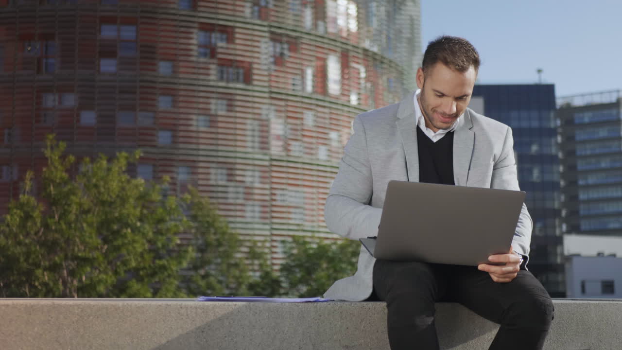 un hombre de negocios leyendo buenas noticias en una computadora portátil en la calle.