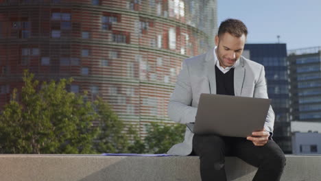 Businessman-reading-good-news-on-laptop-at-street