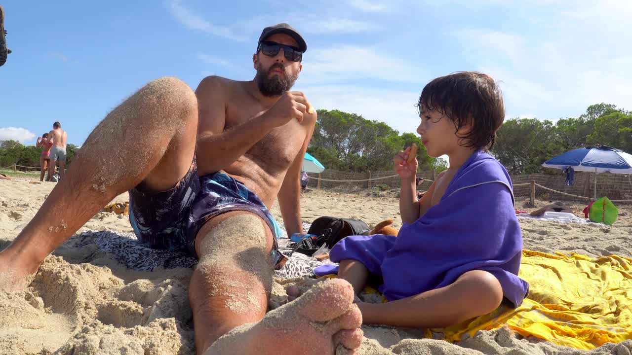 Father and Son Enjoying Snacks on the Beach