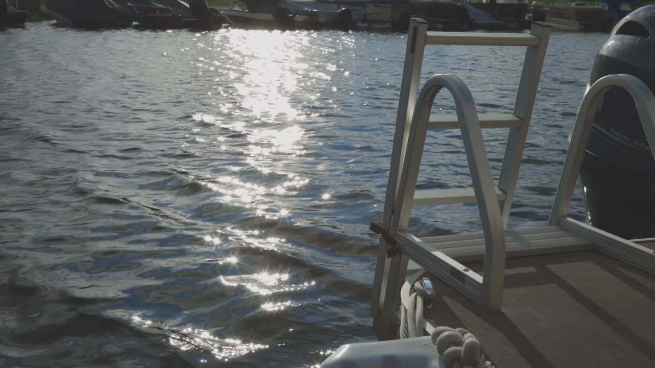 Metallleiter auf dem Achterdeck eines Segelboots mit kräuselndem Wasser und Sonnenlichtreflexionen auf dem Hintergrund im Sommer. - statische Aufnahme