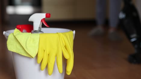 4k-video-footage-detergents-in-a-bucket-on-the-floor-and-woman-cleaning-her-home-in-the-background