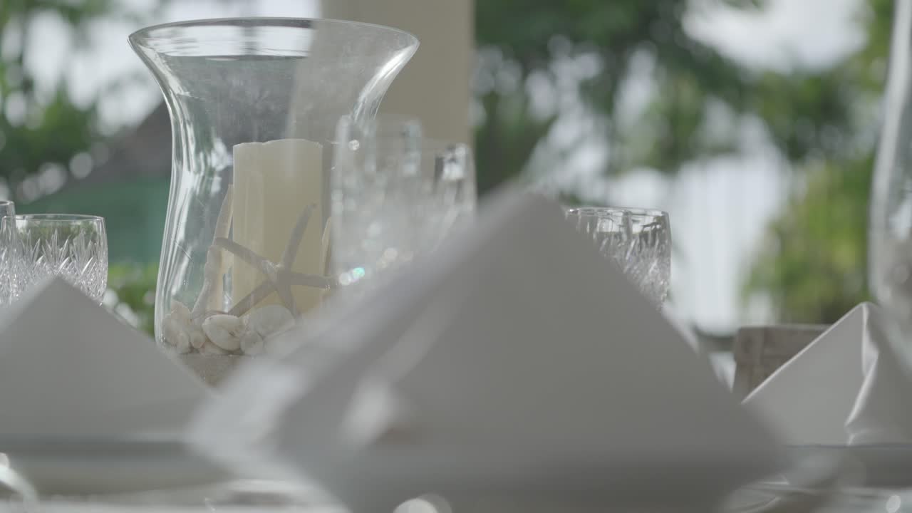 Waiter setting the table with crystal glassware next to fine flatware