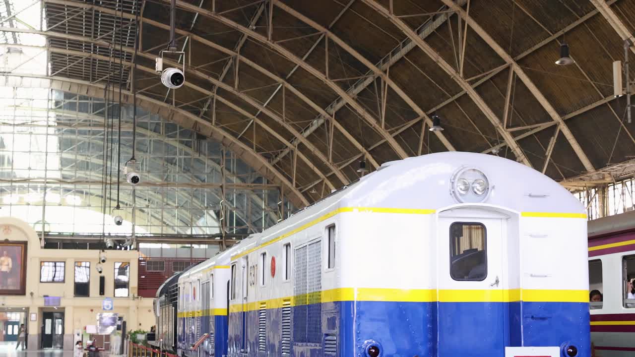 Static shot of restored colorful vintage train inside bright historic Bangkok railway hall