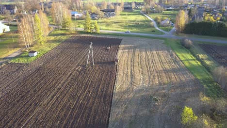 Landwirtschaftlicher-Traktor,-Der-Schmutzfeld-In-Der-Landwirtschaftlichen-Gemeinschaft-Pflügt---Antenne