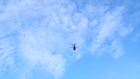 helicóptero pasando desde un ángulo bajo en el cielo azul nublado