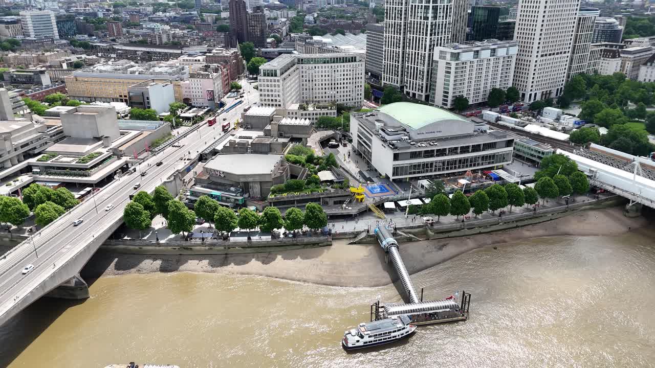 Aerial pan of London’s busy South Bank, iconic Festival Hall, Festival Pier, and Thames River, showcasing London’s architectural charm.