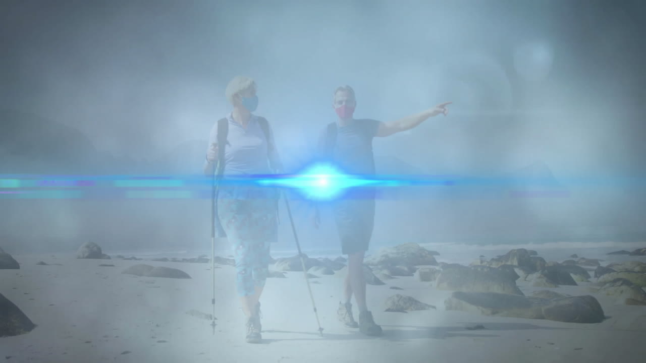 Couple walking beach with face masks, trekking poles, showing animated health chart and heart icon