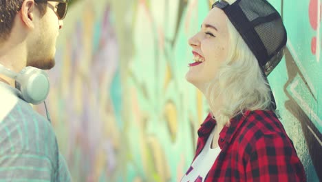 two hipster friends chatting in front of graffiti